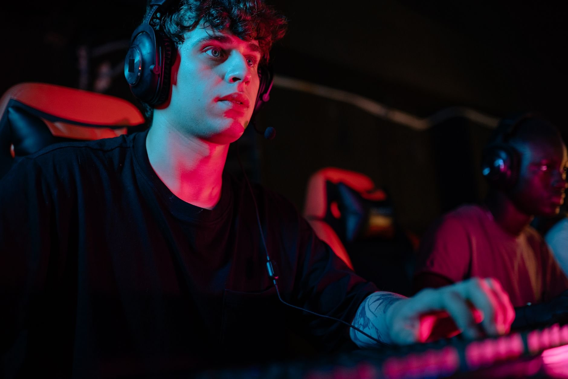 Focused young man gaming with headset at PC gaming setup, showcasing intense concentration